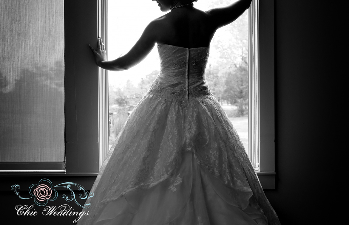 a woman in a wedding dress standing in front of a window