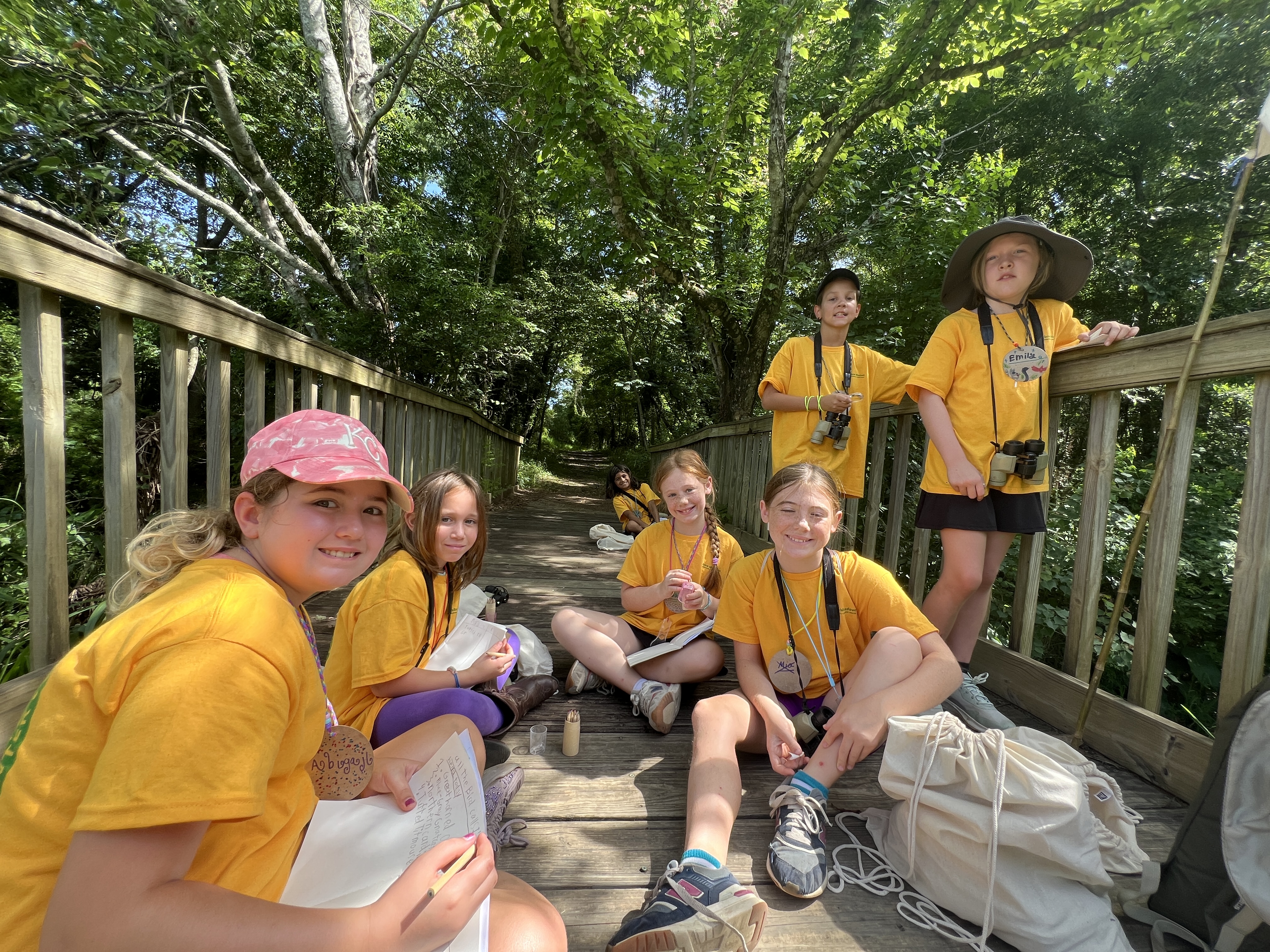 Kids in yellow shirts sitting on bridge