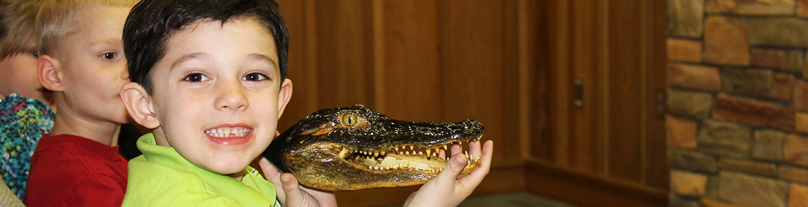 a boy holding an alligator head