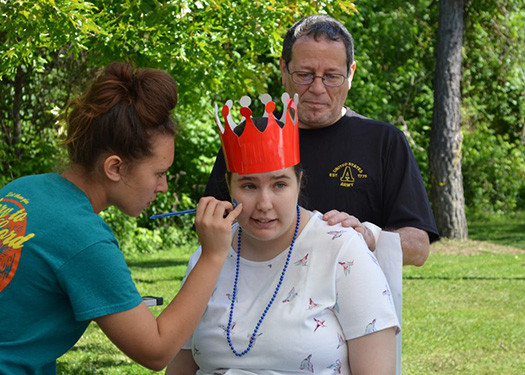 a girl having her face painted with a person standing behind her