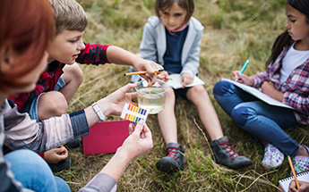 children sitting on the ground performing a science experiment