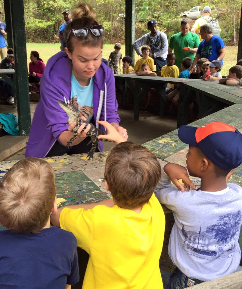 woman showing children a baby alligator